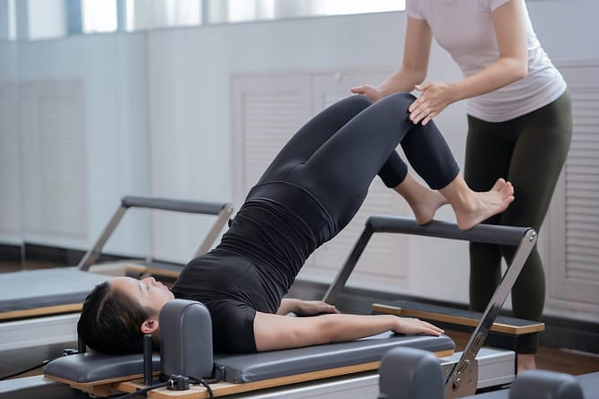 A lady performs an exercise with reformer Pilates tools